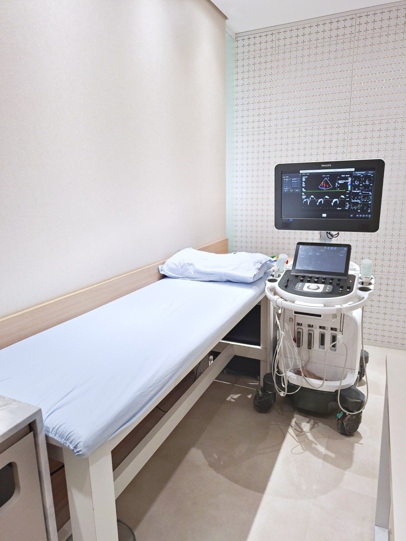 Sala de ecocardiograma: maca preparada e o aparelho de ultrassom com a imagem do coração na tela.
